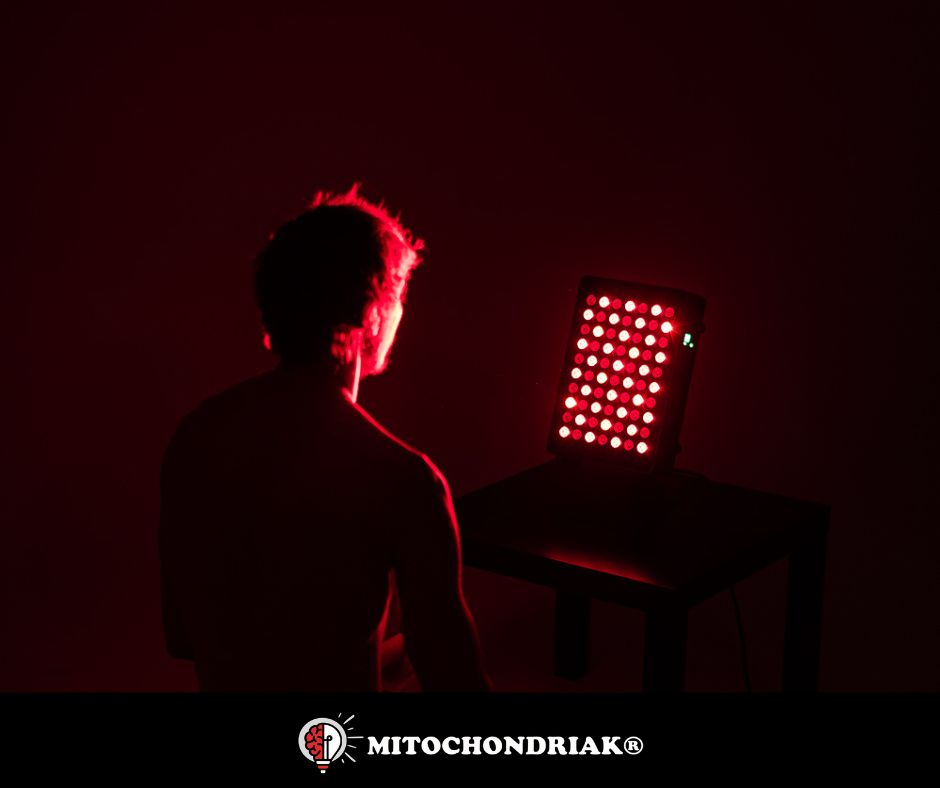 Mann sitzt von hinten gesehen im abgedunkelten Raum vor einem kleinen LED-Panel auf einem Tisch, dessen einzelne rote LEDs deutlich zu erkennen sind
