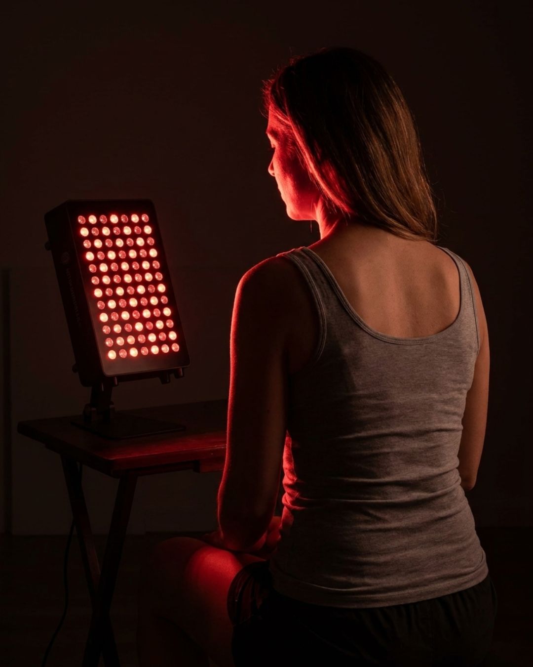 Woman using a red light therapy panel for a face and skincare session